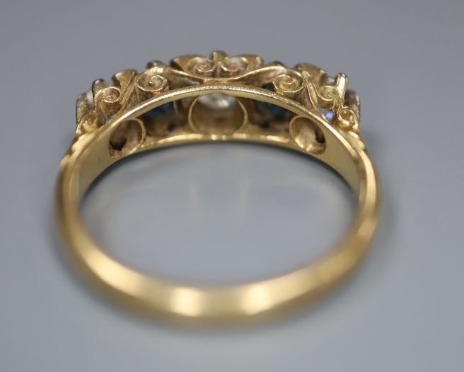 An early 20th century 18ct gold three stone diamond and two stone sapphire set half hoop ring, size K, gross 3.6 grams.